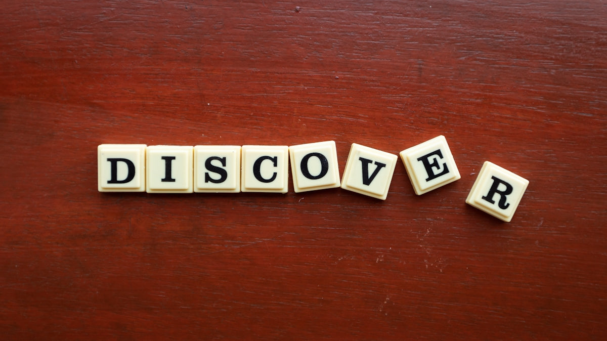 the word discovery spelled with scrabble letters on a wooden surface