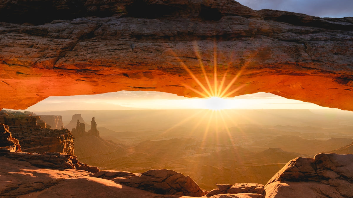 the sun is shining through an arch in the desert