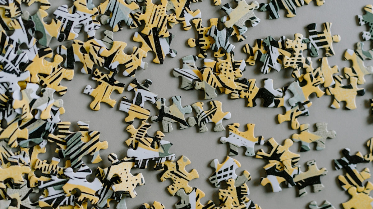 Scattered puzzle pieces with yellow and grey abstract patterns