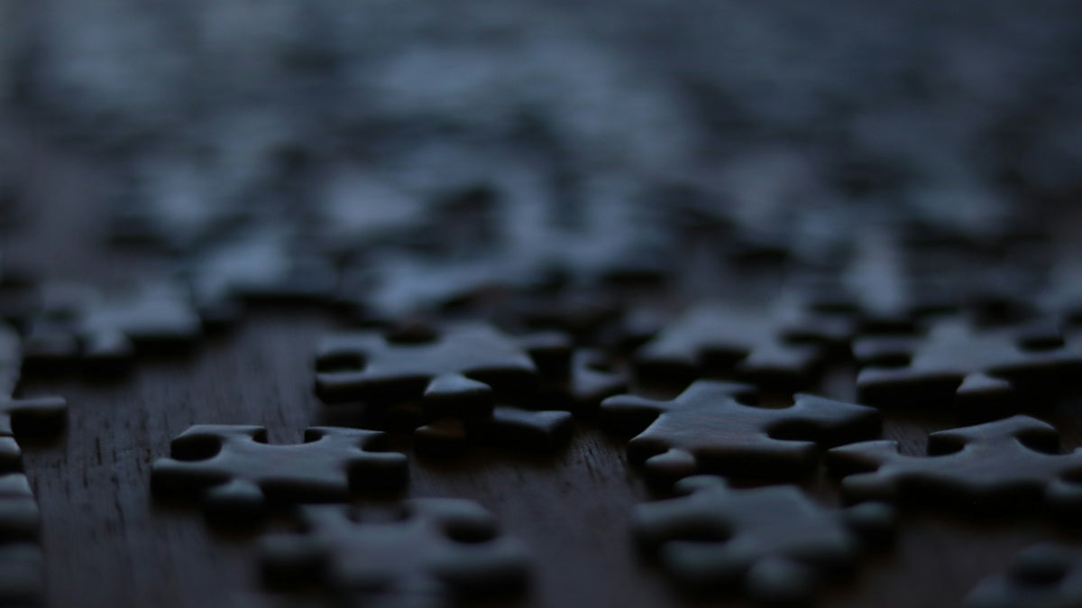Scattered puzzle pieces on a dark wooden surface