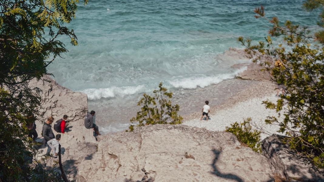 People relax on rocky shore by clear blue ocean