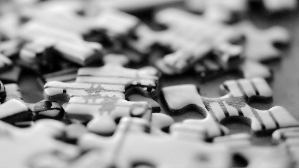 Many scattered jigsaw puzzle pieces in black and white