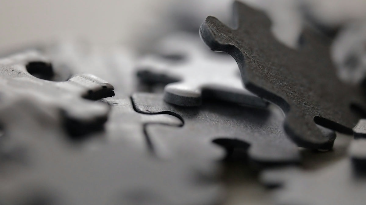 Scattered dark gray puzzle pieces with one piece slightly raised
