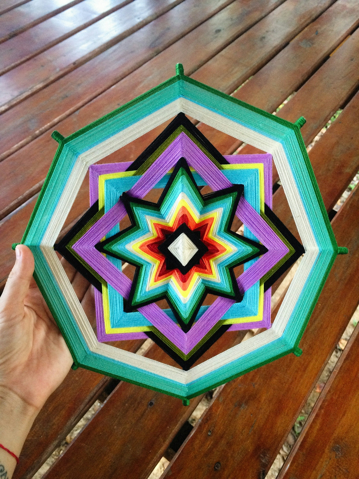 a person holding a colorful umbrella on top of a wooden table
