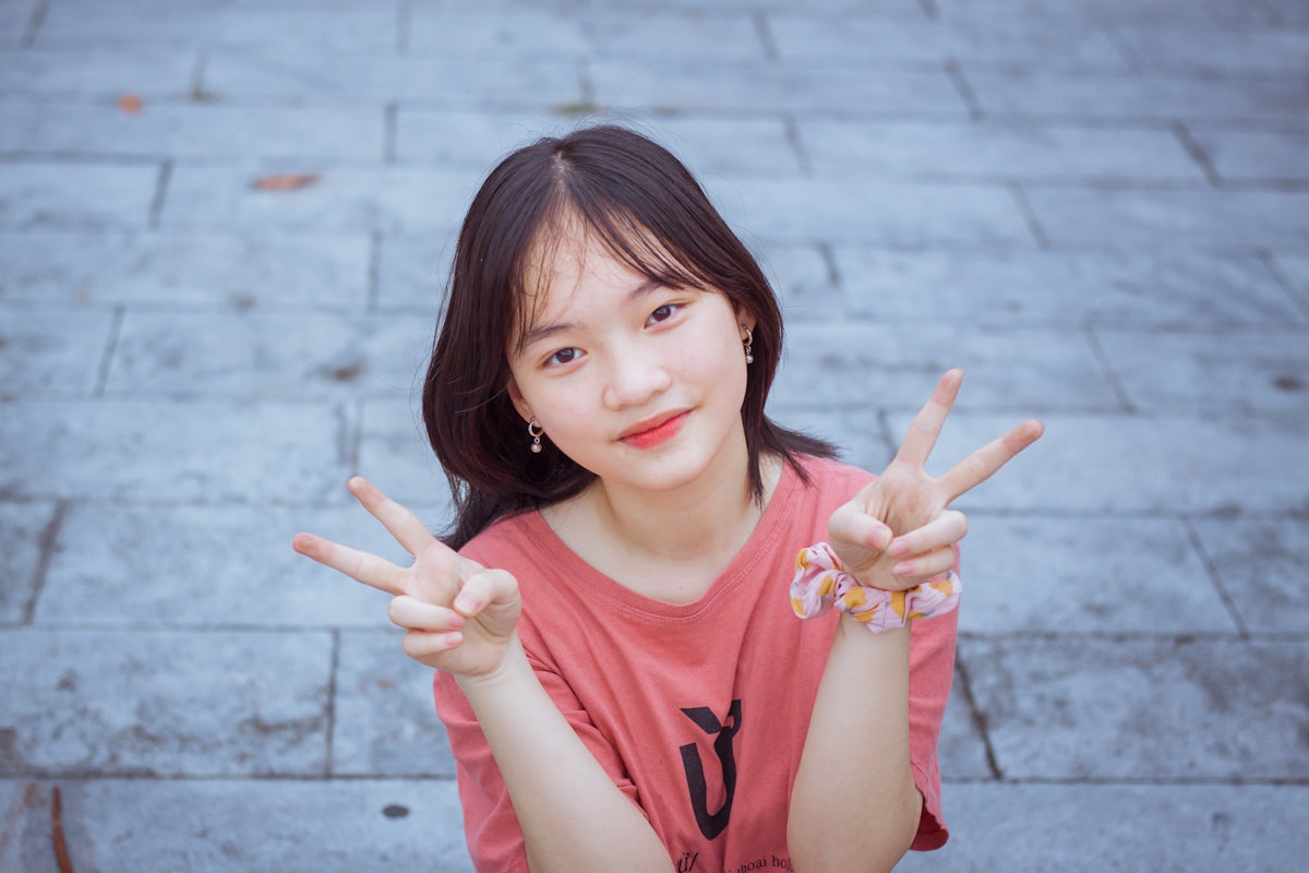 a young woman sitting on the ground making a peace sign