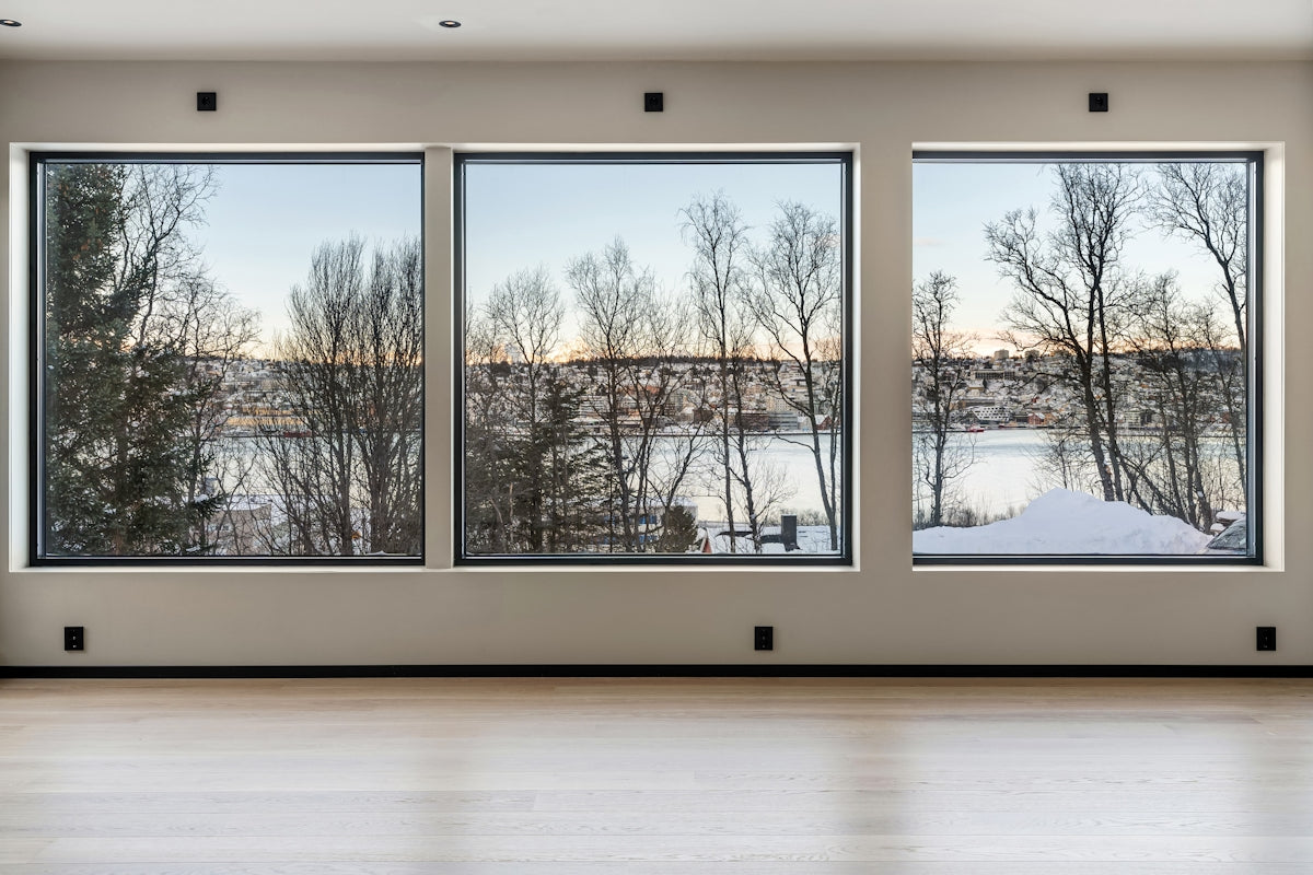 An empty room with three windows and a view of a river