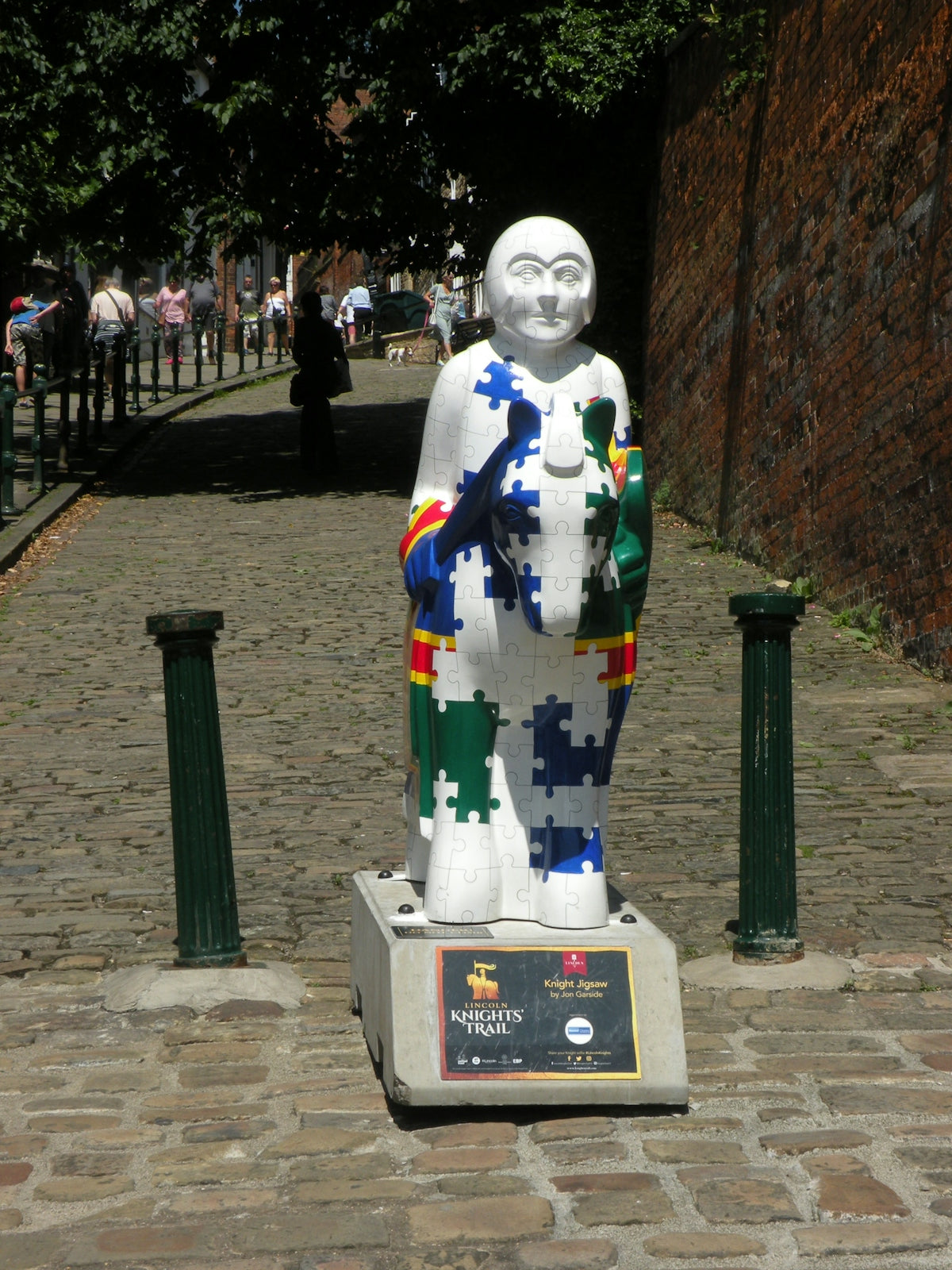 Statue decorated with colorful puzzle pieces on cobblestone street