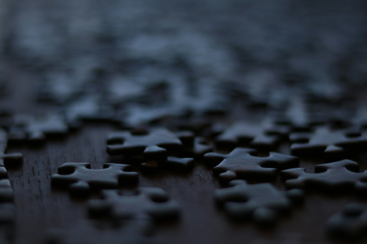 Scattered puzzle pieces on a dark wooden surface
