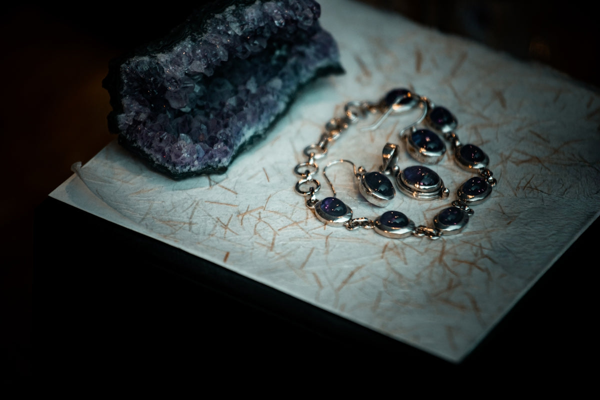 Amethyst jewelry and raw crystal on textured paper
