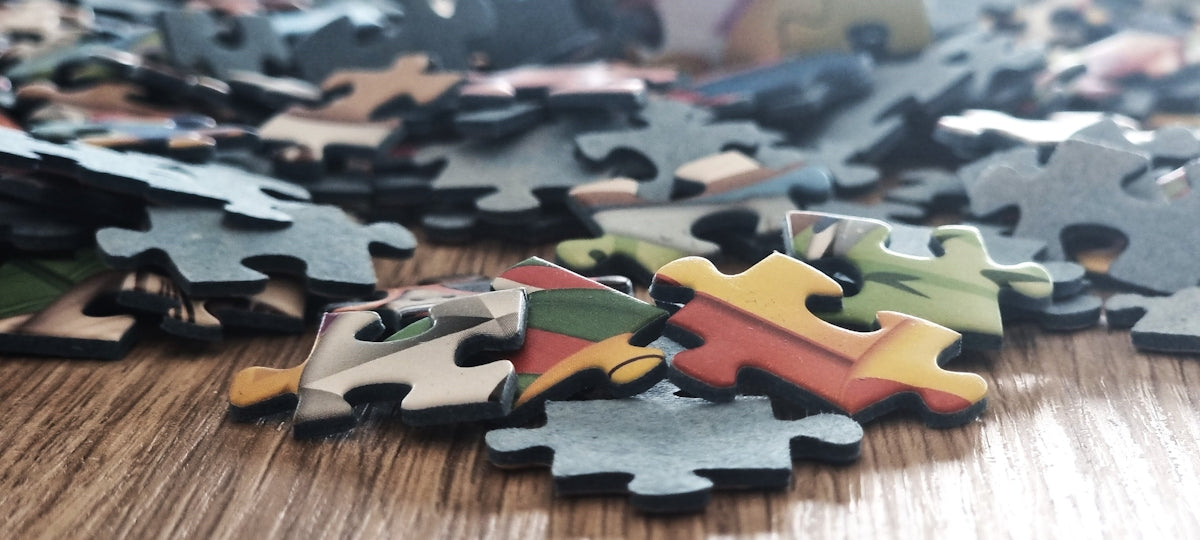 Scattered colorful puzzle pieces on a wooden surface.