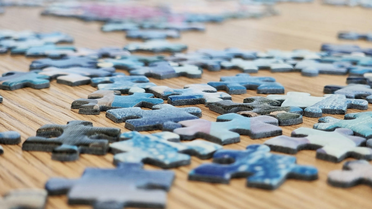 Scattered blue puzzle pieces on a wooden surface.