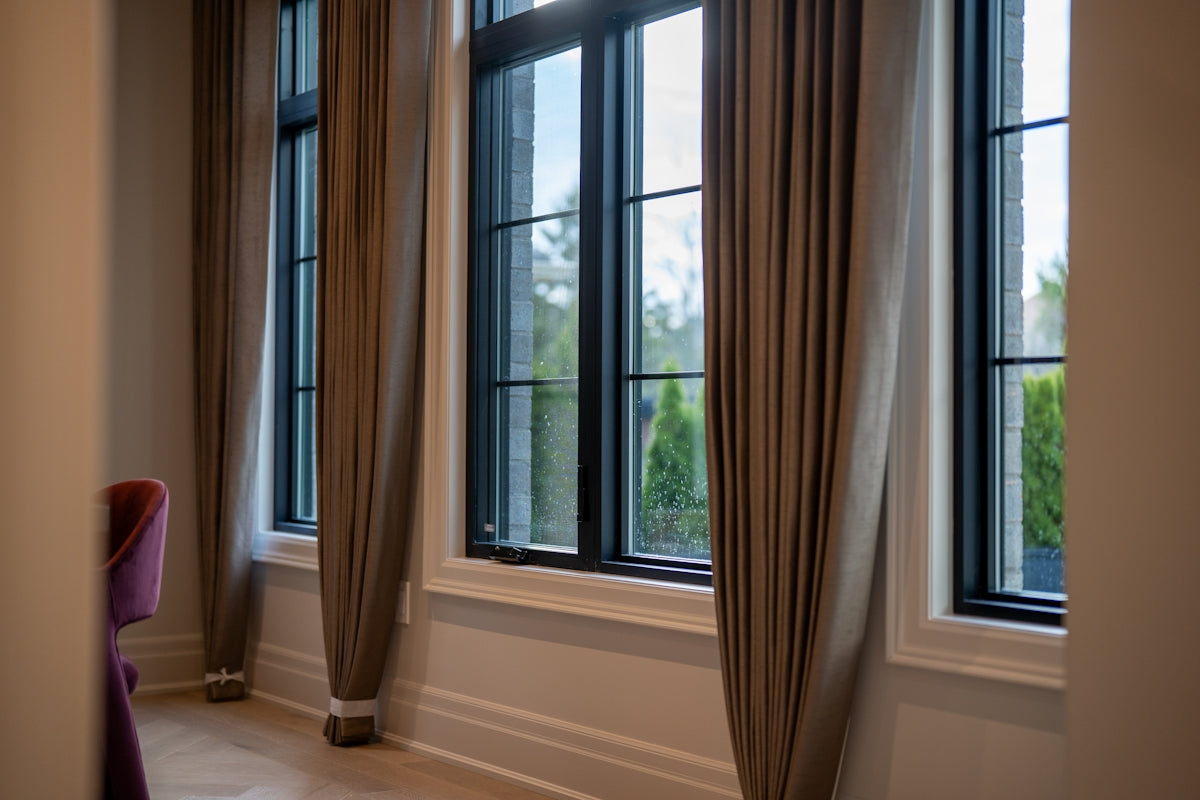 Large windows with beige curtains in a room.