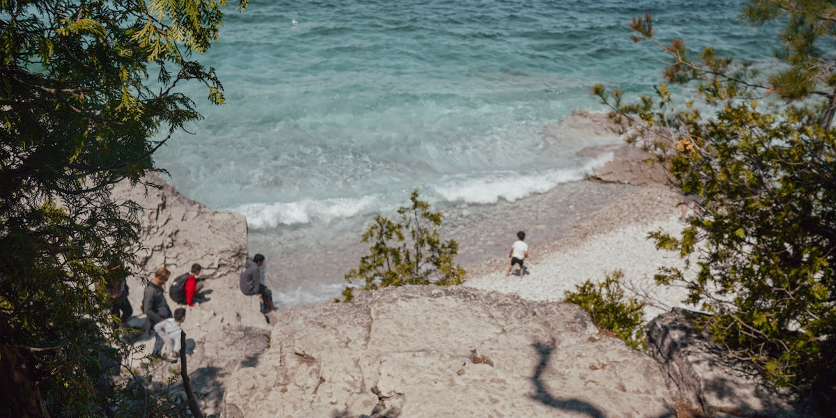 People relax on rocky shore by clear blue ocean