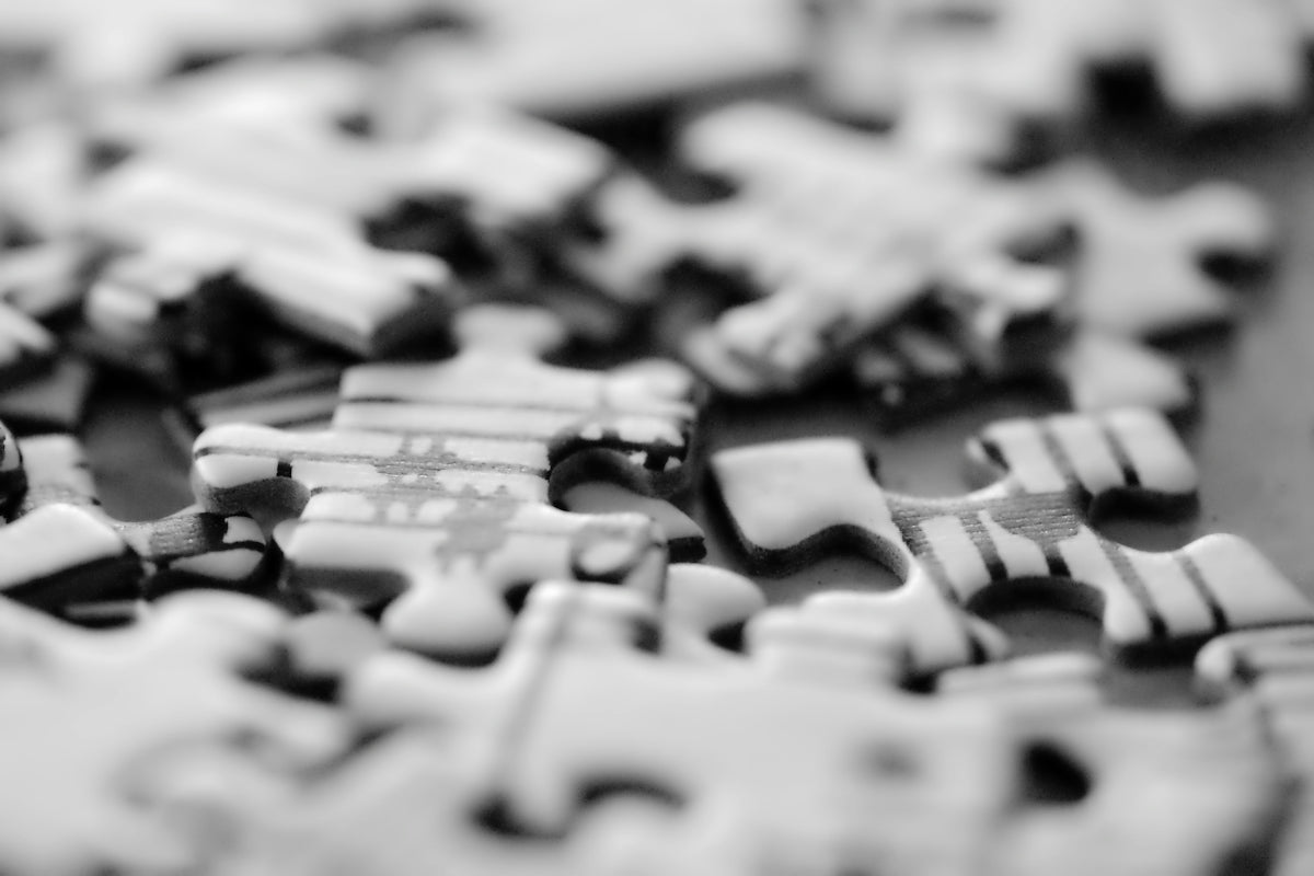 Many scattered jigsaw puzzle pieces in black and white