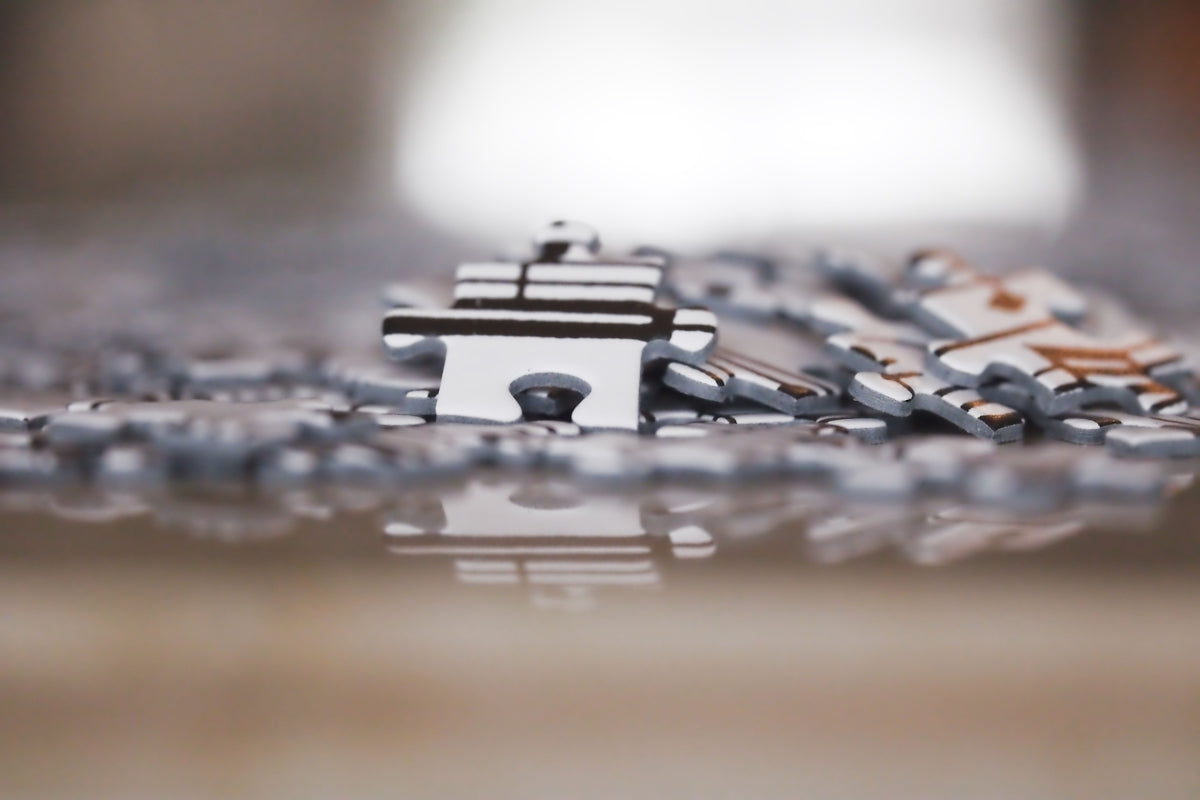 Scattered puzzle pieces on a reflective surface, one standing upright