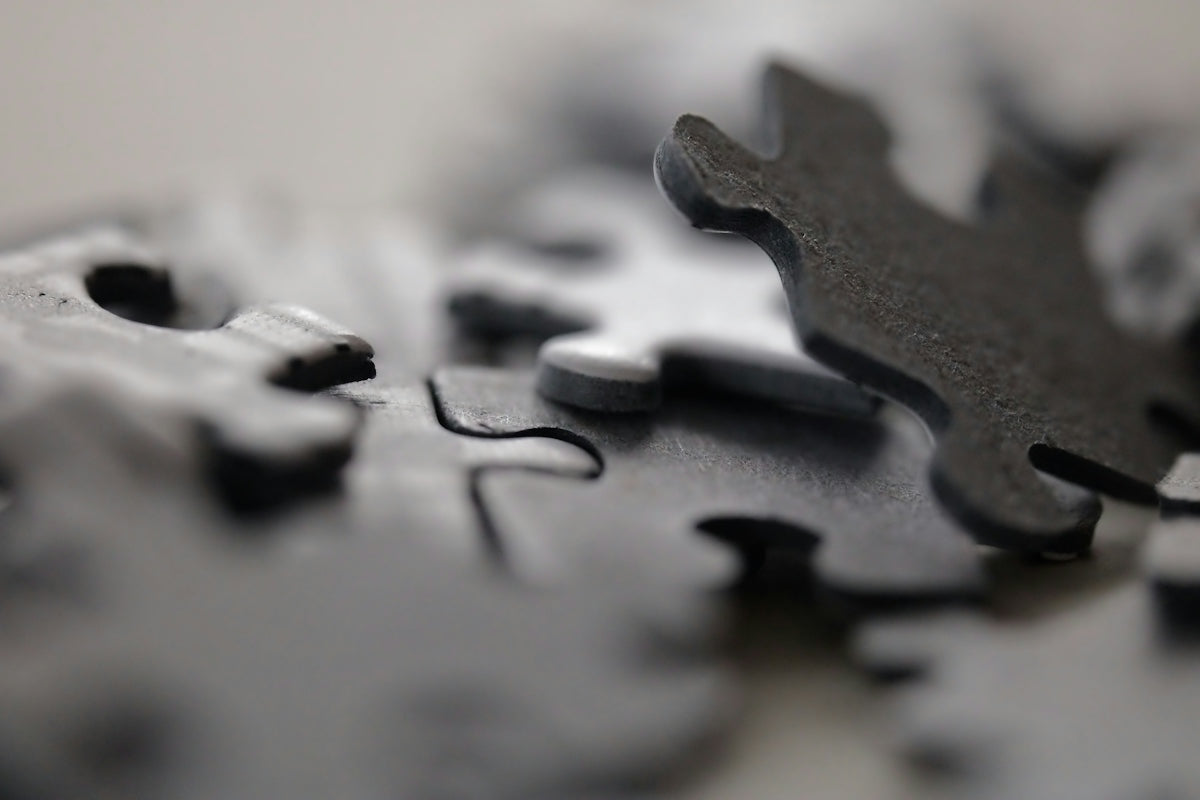 Scattered dark gray puzzle pieces with one piece slightly raised